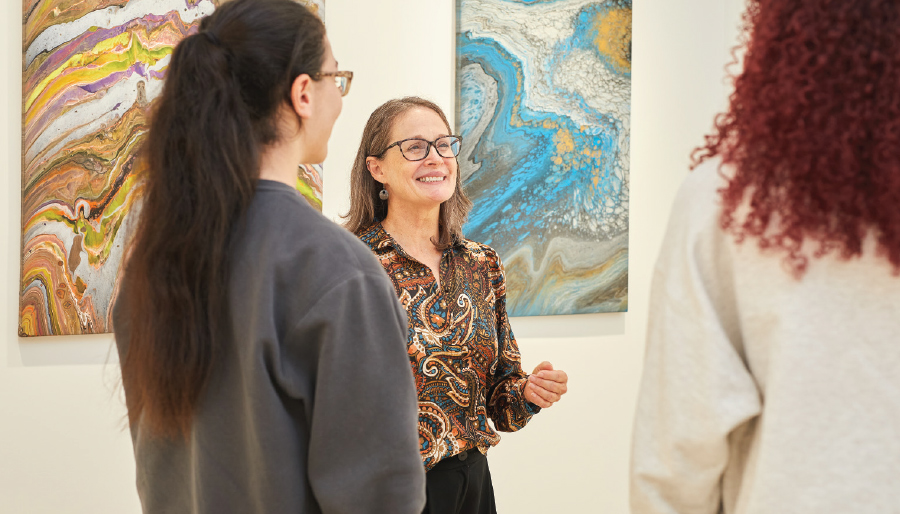 three women speaking and smiling in art gallery