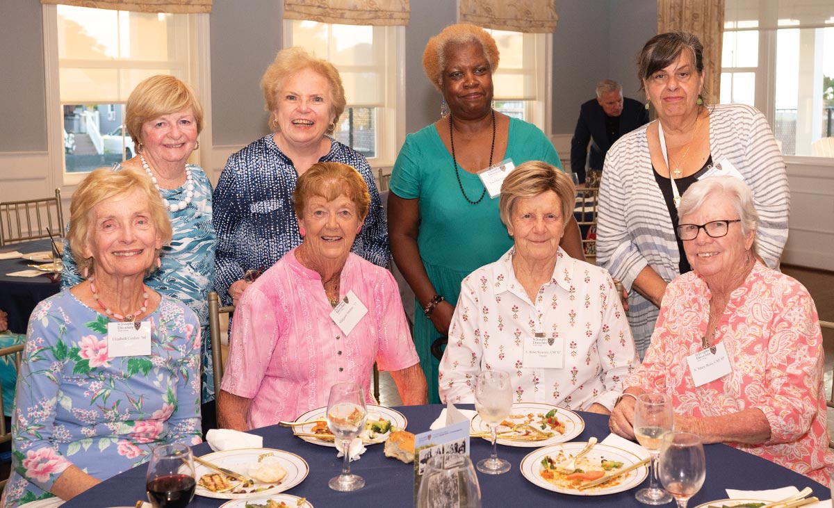 Group of six alumni gathered at a table during the annual Breezy Point/Rockaway Reception