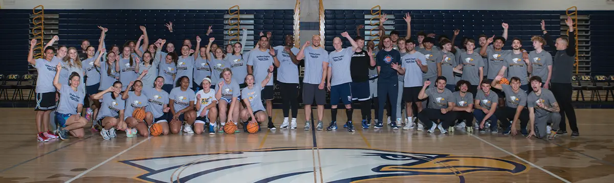 athletes posing with their hands in the air inside a basketball court