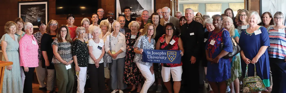 alumni and President Boomgaarden posing together at the Belle Harbor Yacht Club