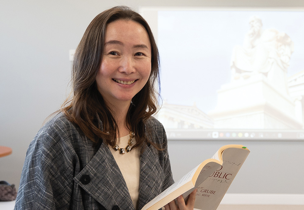 Eunah Lee smiling while holding a paperback book in a course room