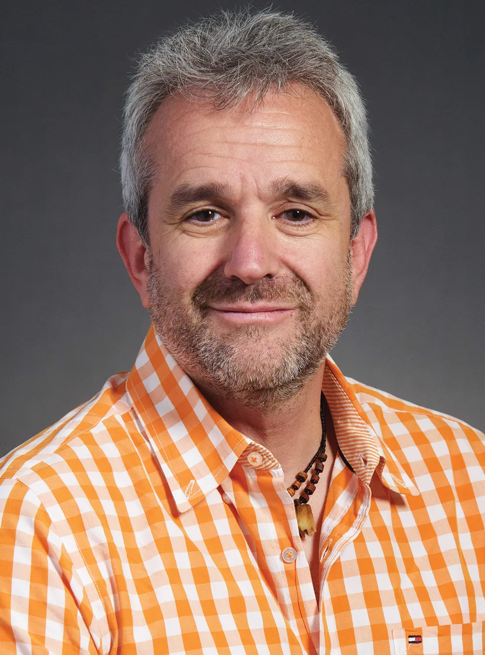 headshot of Seth Armus wearing a orange and white checkered button up