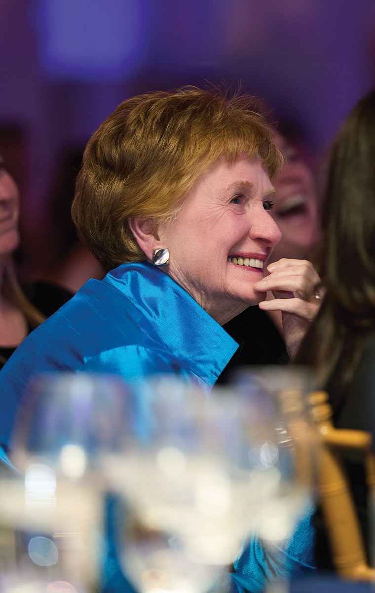 candid shot of Dr. Mary B. Mulvihill seated among the audience, smiling as she enjoys the celebration