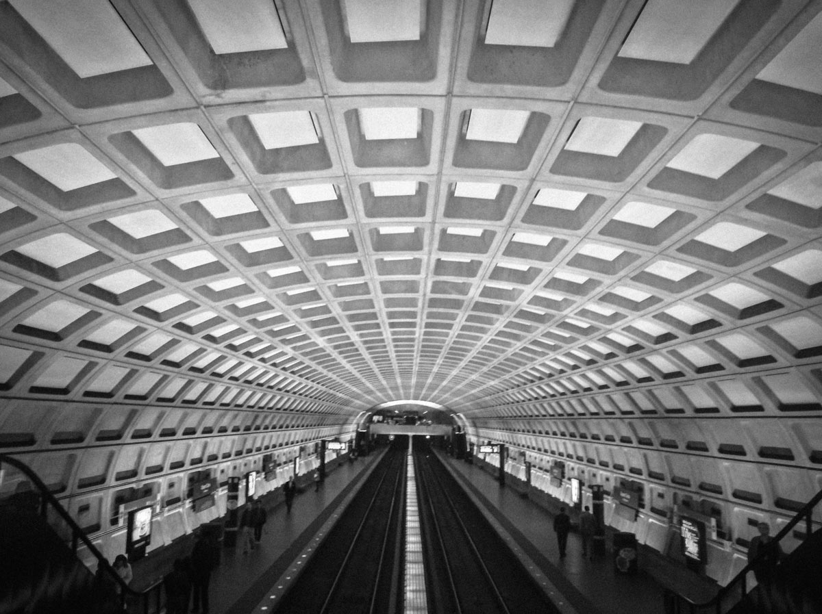 Black and white underground subway station with an arched ceiling and grid pattern.