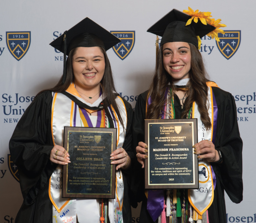 two female graduates with plaques