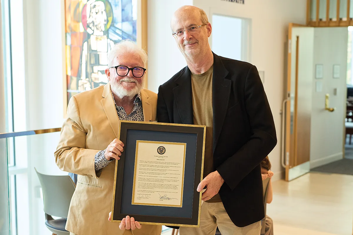 John Roth and Christopher R. Carroll posing together and holding a framed certificate.
