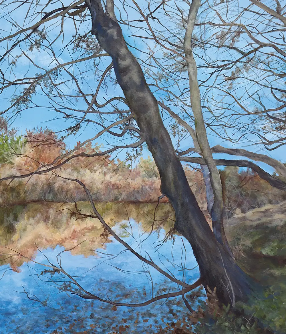 A painting of a tall, leaning tree with bare branches against a bright blue sky. Below, a calm body of water reflects the golden-brown autumn colors of the distant shoreline and the sky.
